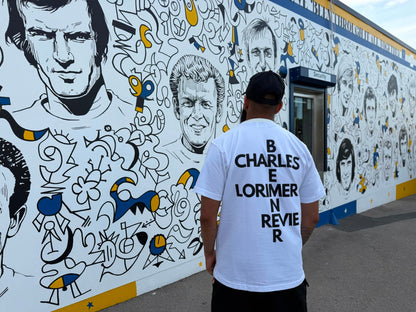 Back of Ananya Garms Bremner & Co white heavyweight T-shirt beside Billy Bremner statue at Elland Road